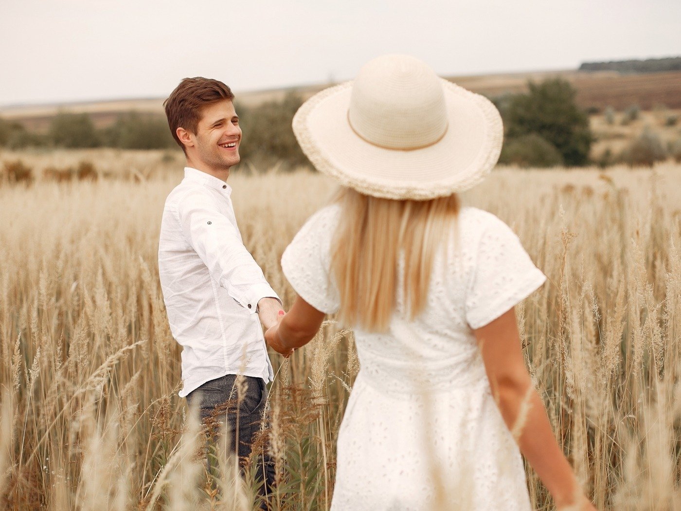 Cute couple in a field. Lady in a white dress. Guy in a white shirt